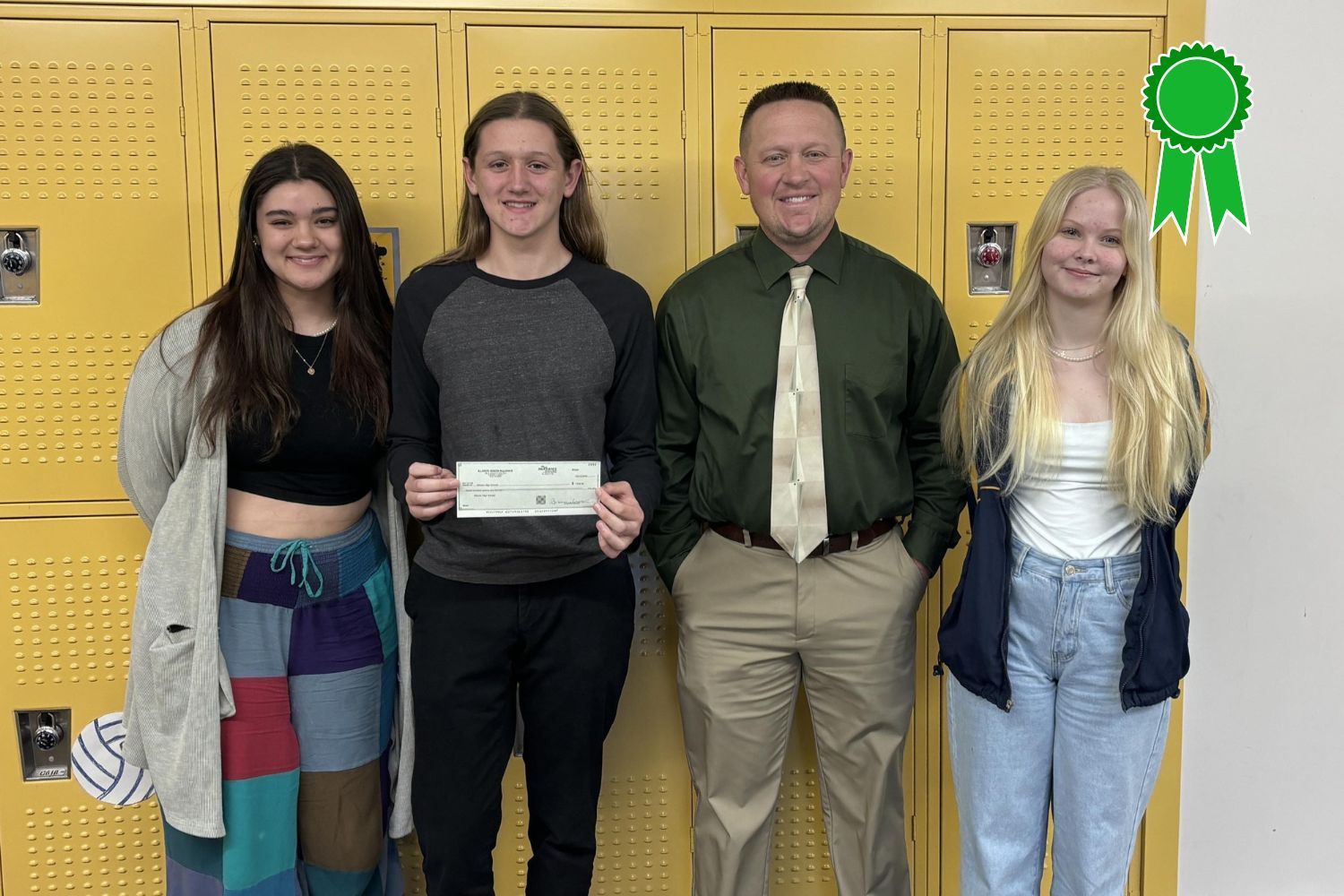A group of people standing next to each other in front of yellow lockers holding a check.