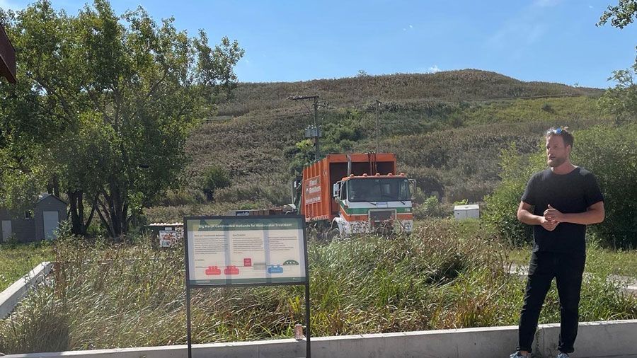 A man is standing in front of a garbage truck.