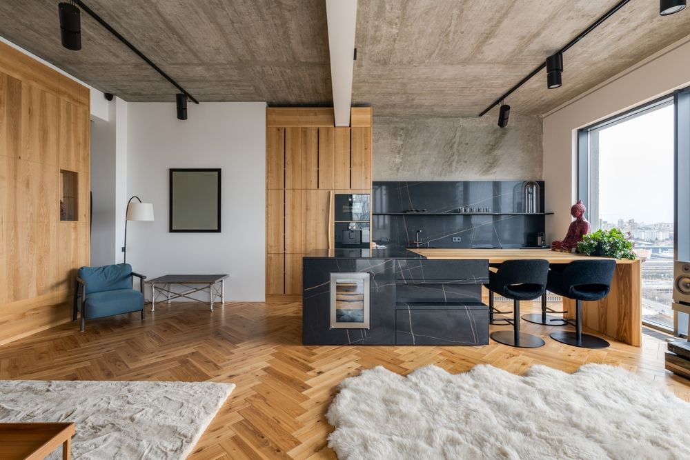 Modern kitchen and living area with wood and stone elements, a large window, and a rug.