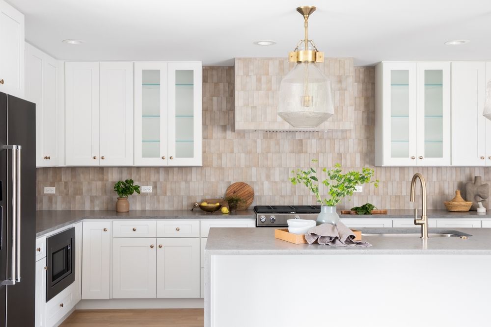 White kitchen with gray countertops, island, and beige tiled backsplash.