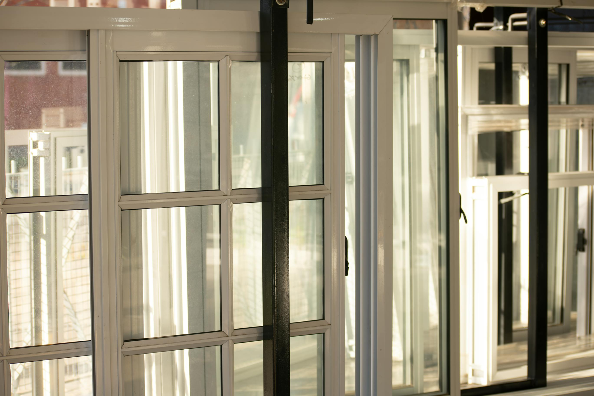 White framed sliding glass doors with multiple window panes, sunlight illuminating the interior.
