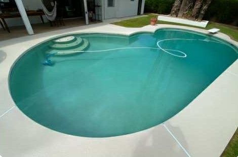 Swimming pool with turquoise water, concrete deck, and steps.