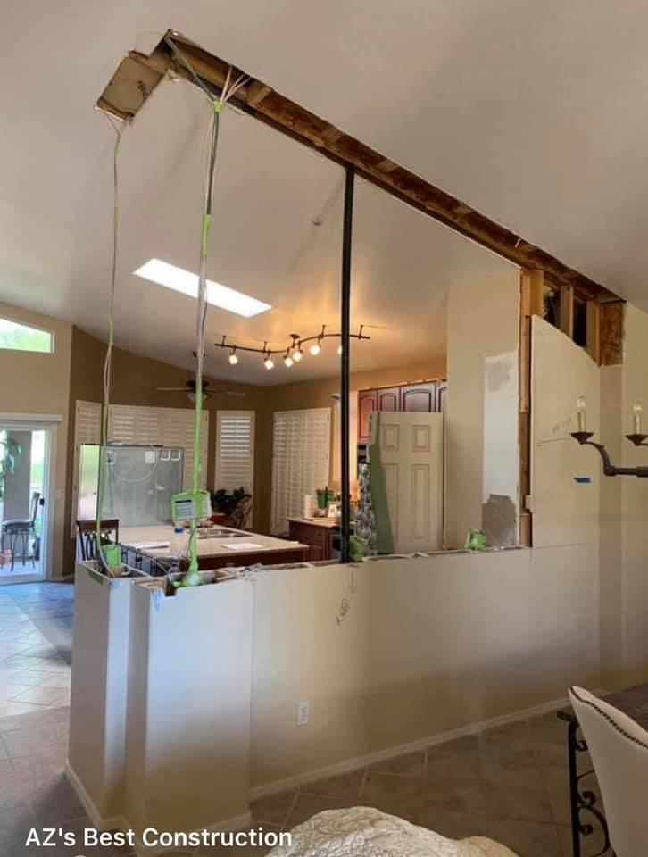 Interior renovation: Wall partially removed, wires hanging, view to kitchen and dining area.