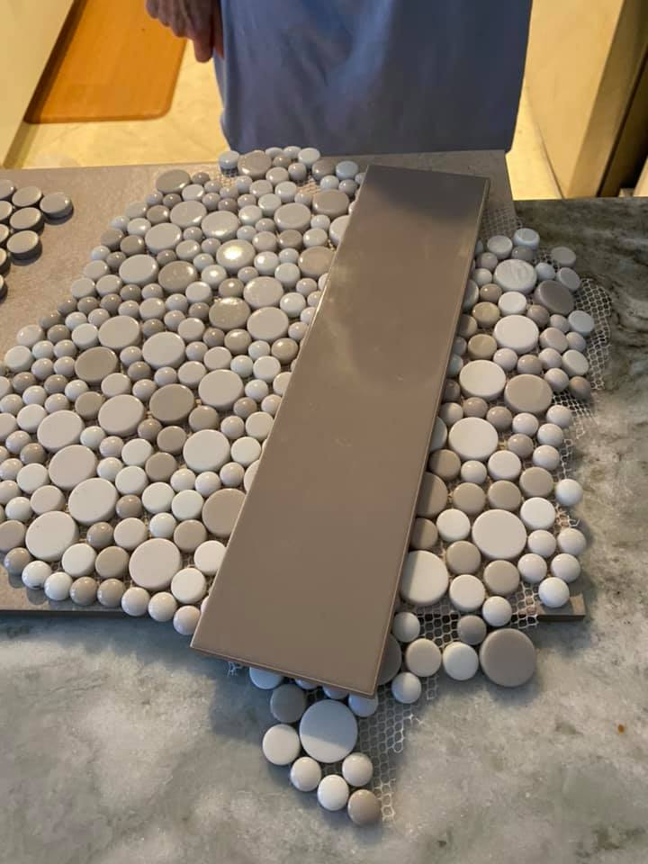 Mosaic tile circles in shades of white and gray with a beige accent tile on a surface.