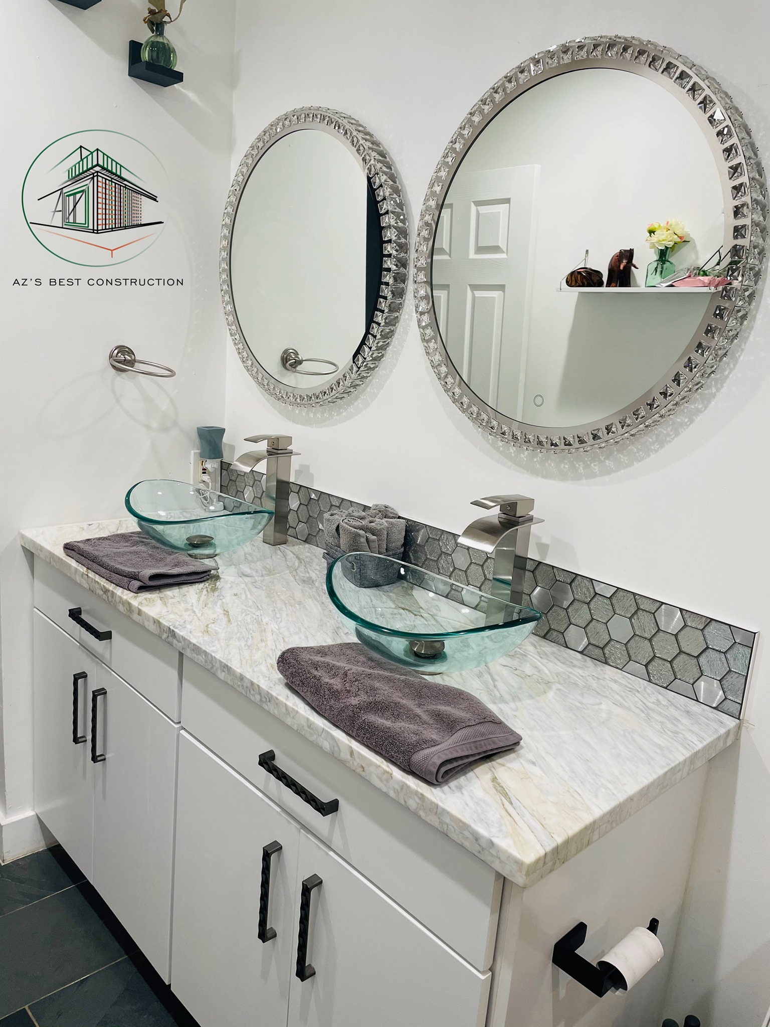 A modern bathroom with two sinks, glass bowls, and crystal-framed mirrors above a white vanity.
