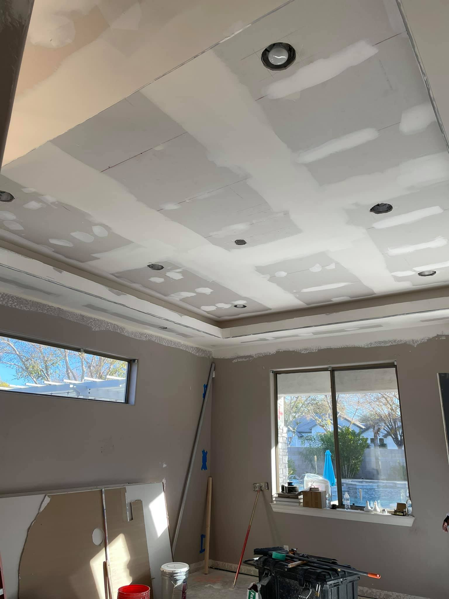 Room under construction; drywall ceiling with recessed lights, window, and partially built walls.