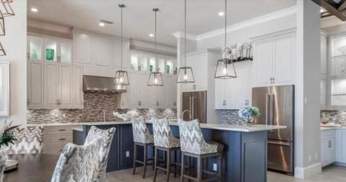 Elegant kitchen with gray cabinets, stainless steel appliances, and a navy blue island with patterned bar stools.