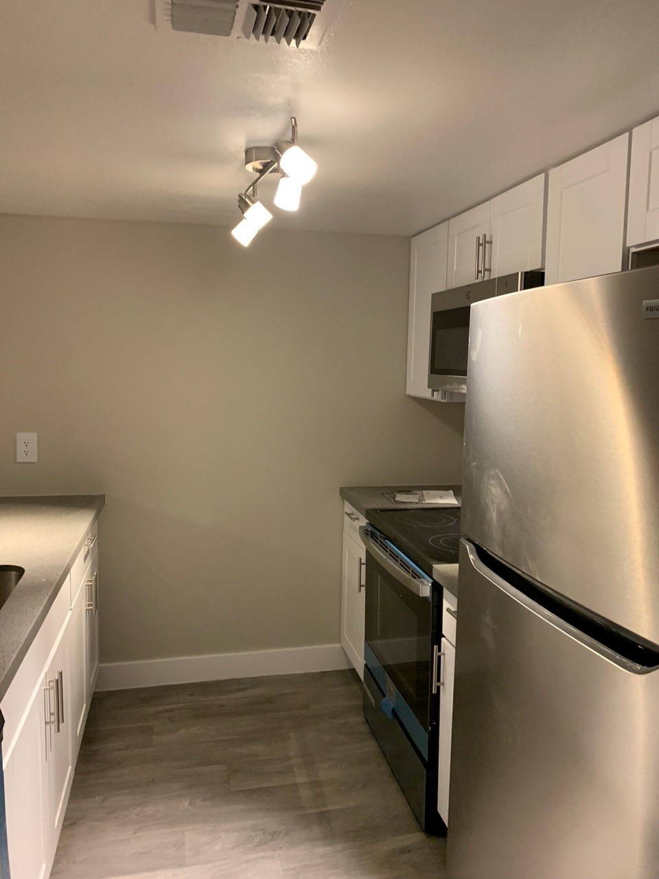 A kitchen with white cabinets, stainless steel appliances, and gray countertops and flooring.