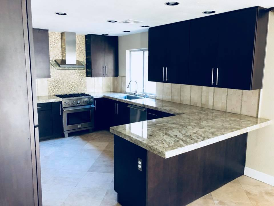 Modern kitchen with dark cabinets, granite countertops, and stainless steel appliances.