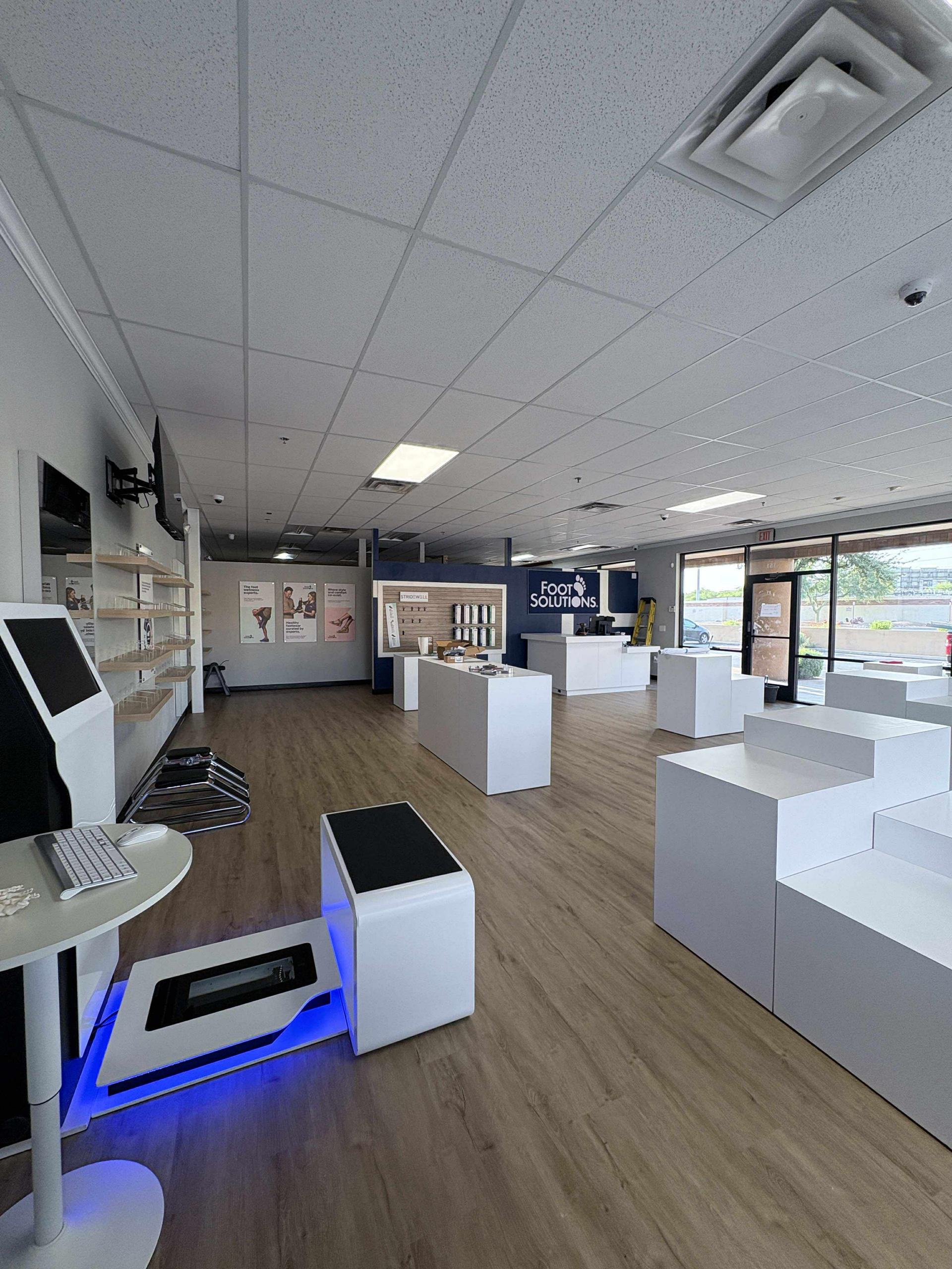 Interior of a white-walled store with product displays, showcasing phones and accessories, with a light-colored wooden floor.