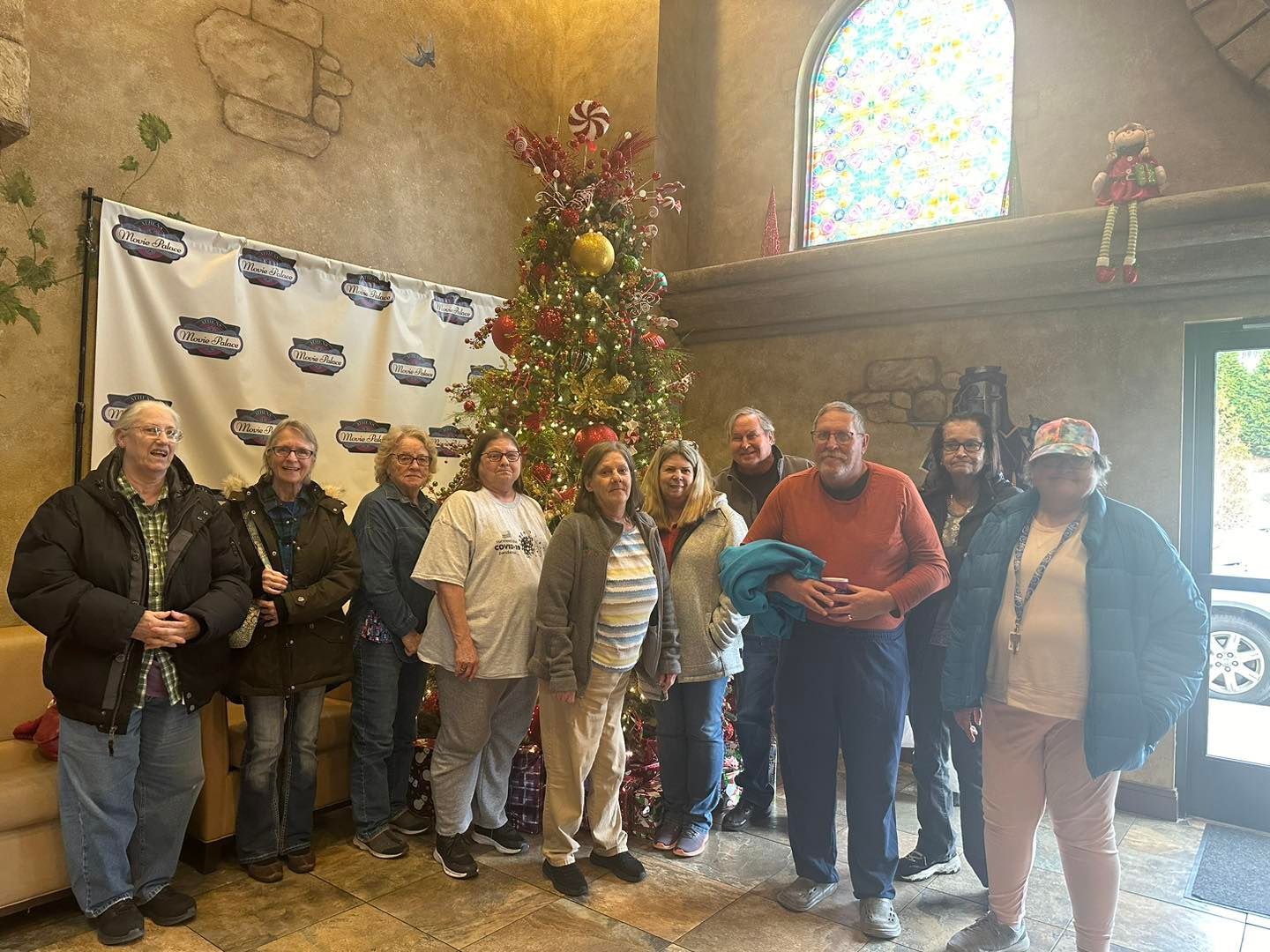 a group of people are standing in front of a christmas tree .