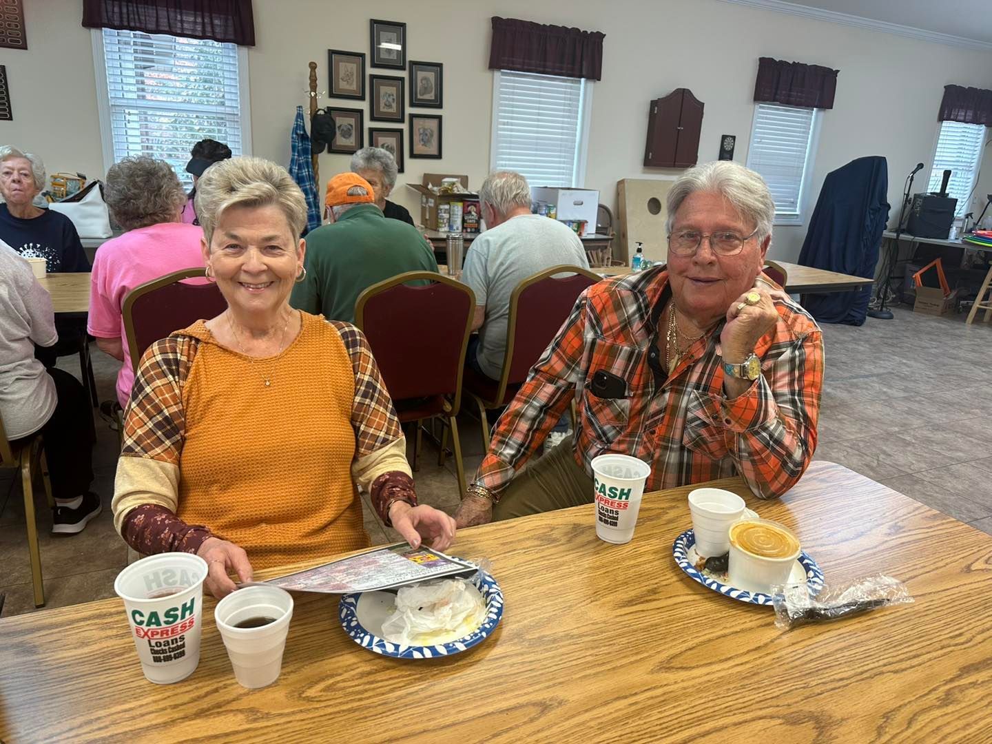 a man and a woman are sitting at a table with cups of coffee .