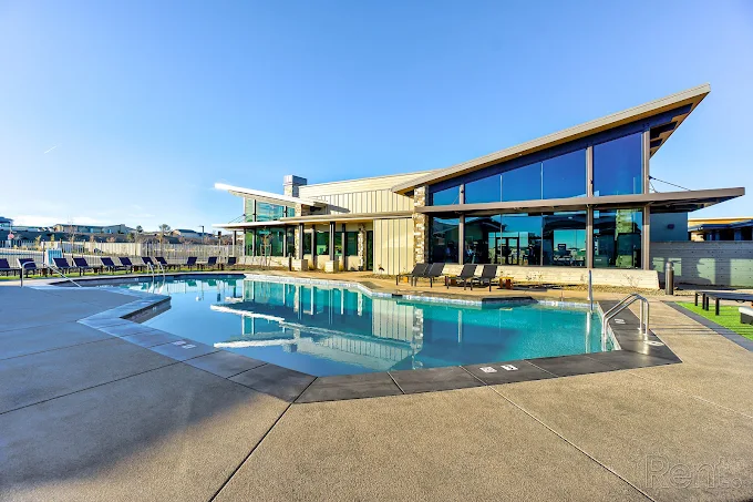 Pool with building featuring large windows, blue sky in the background.