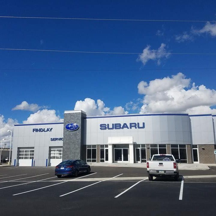 Findlay Subaru dealership under a blue sky, with vehicles parked in front.