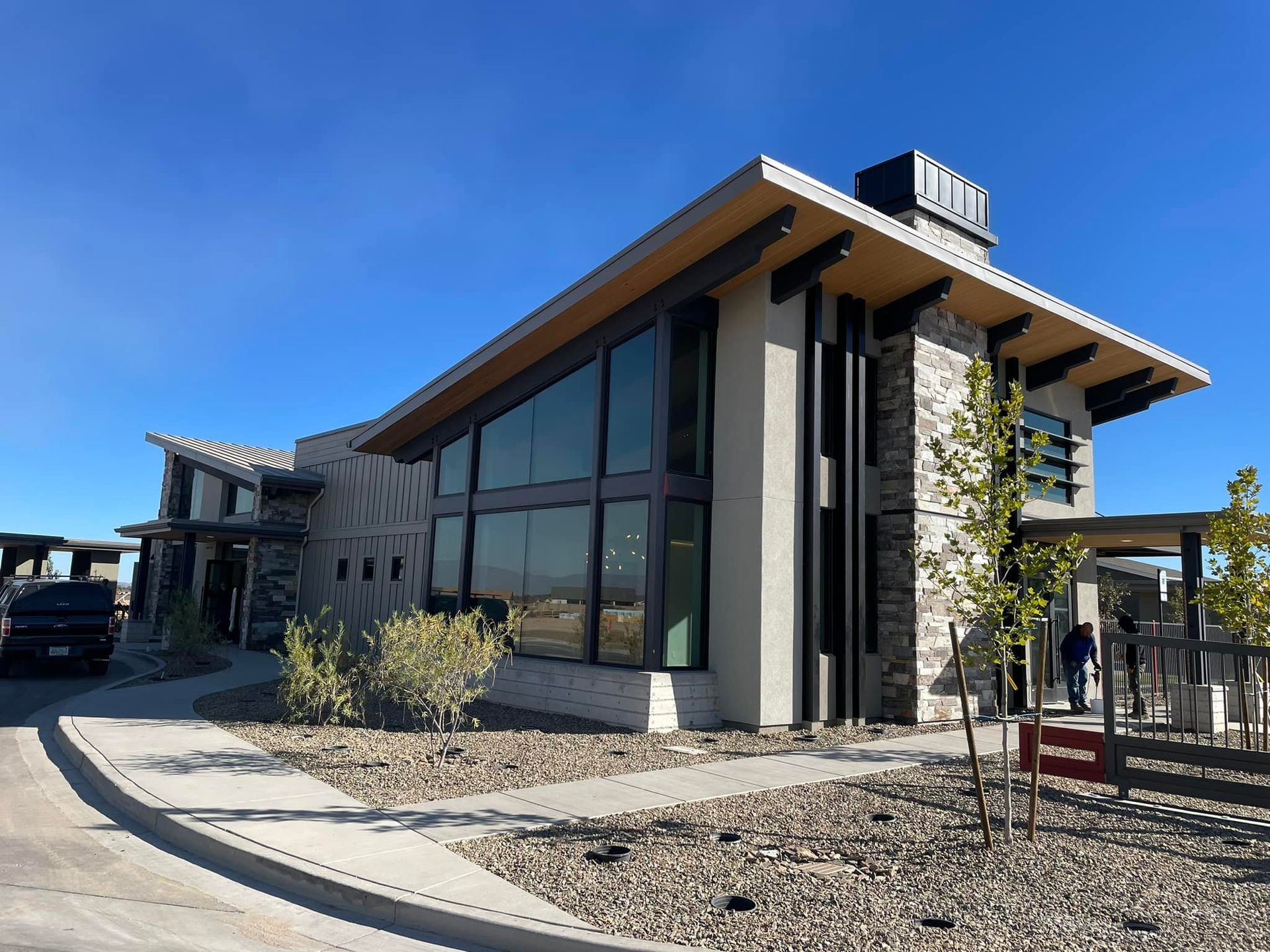 Modern building with stone and glass facade, blue sky, and a paved walkway.