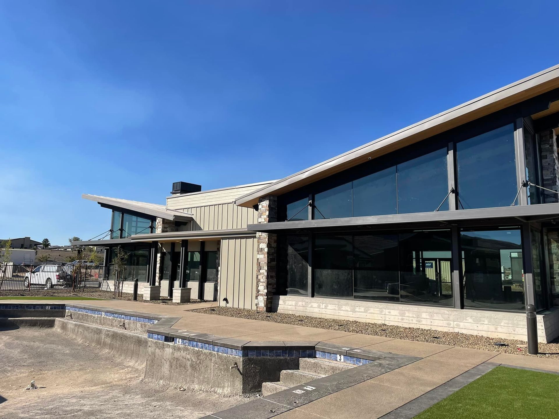 Modern building with large windows and an empty pool on a sunny day.