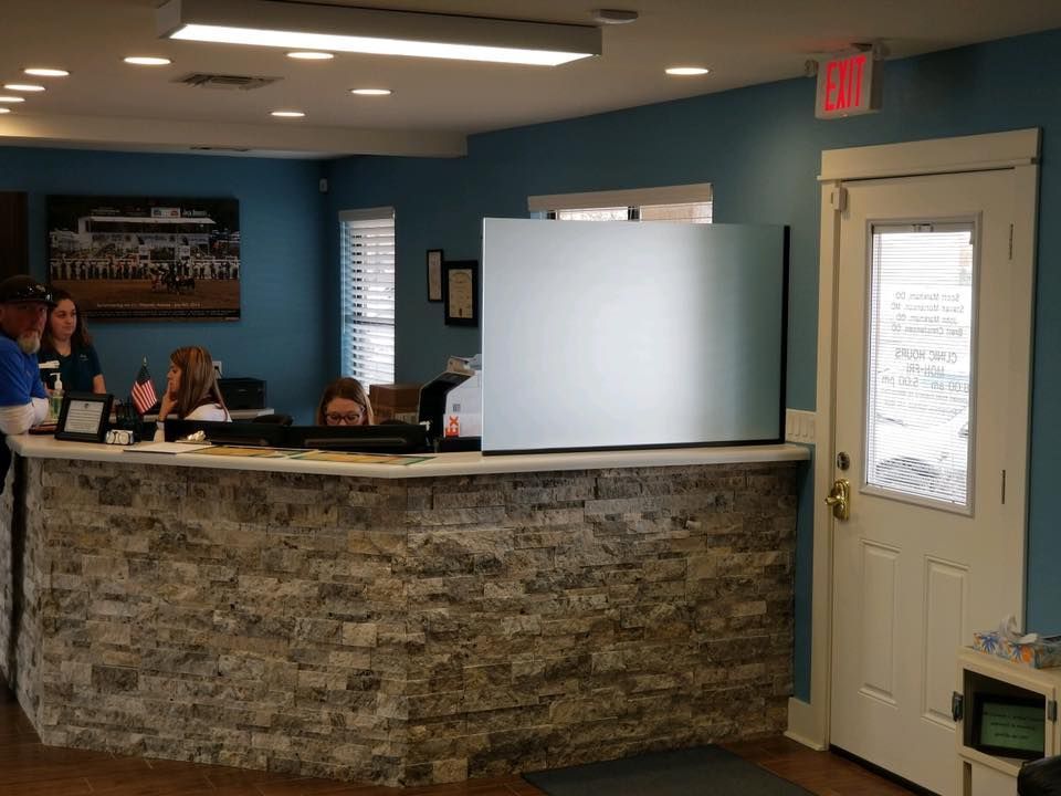 Reception desk in a building with a stone facade, with people behind it and a door to the right.