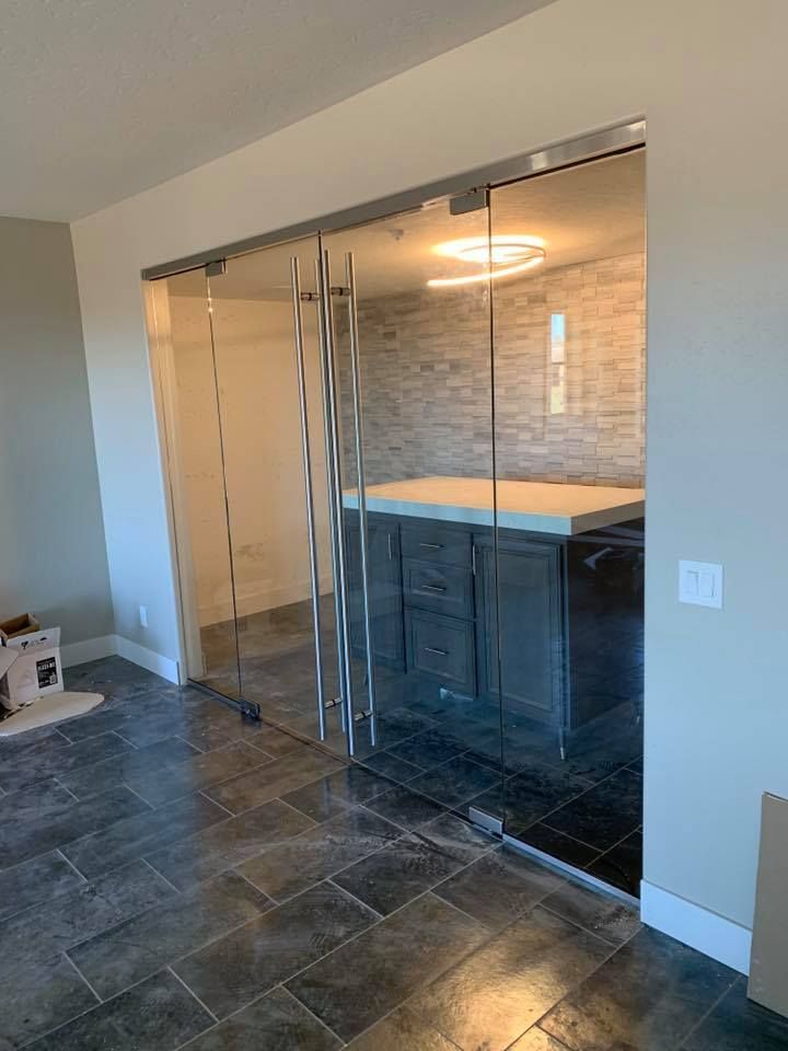 Interior view: Glass sliding doors, dark cabinets, a lit island, and stone wall backdrop.