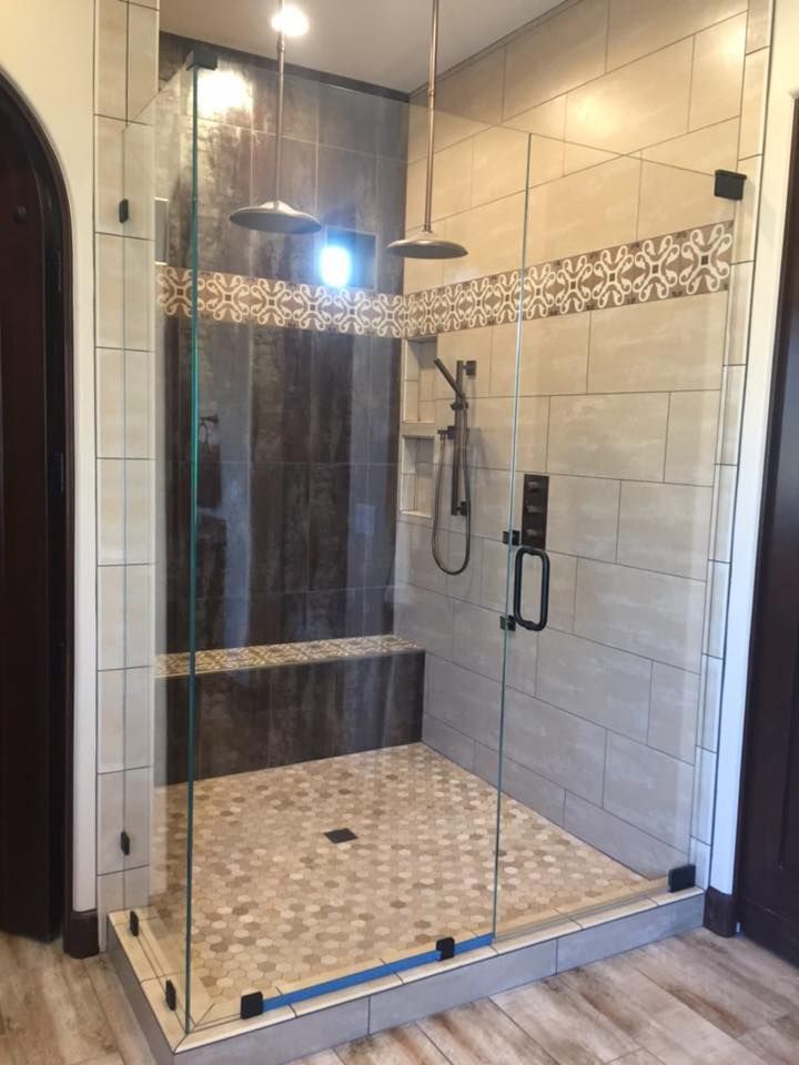 Glass-enclosed shower with bench, multiple showerheads, and decorative tile accents.