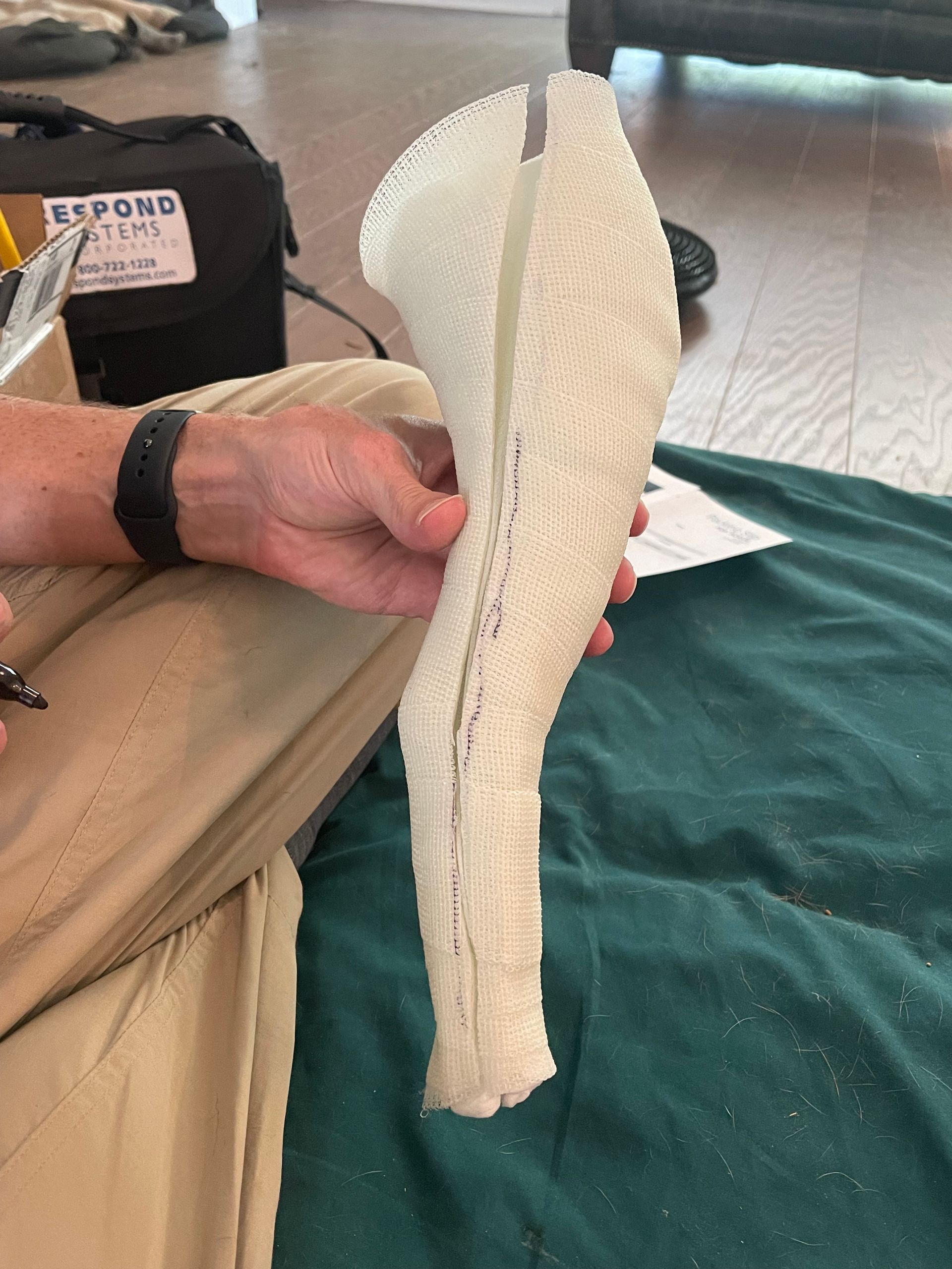 white cast for dog shaped like a leg being held in human hand