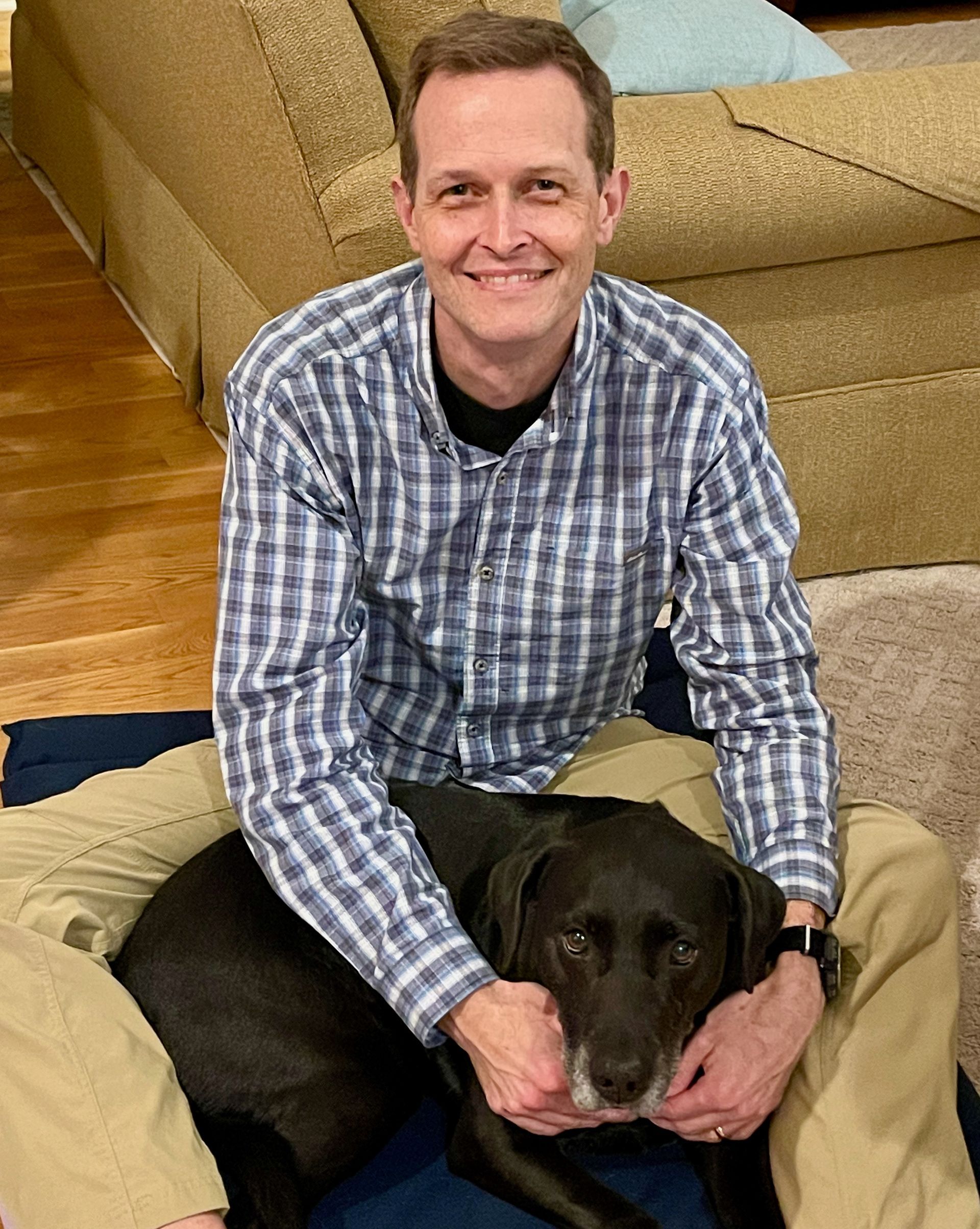 Black dog curled up in lap of male veterinarian on a PEMF mat