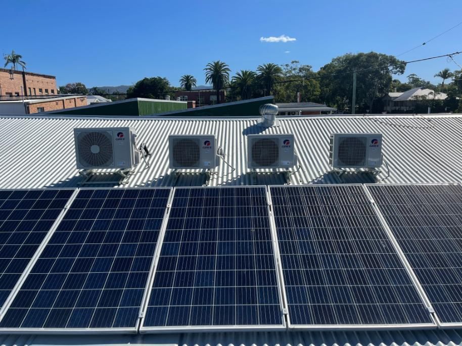 A Row of Solar Panels and Air Conditioners on the Roof of a Building — Condie Refrigeration & Air Conditioning In Ballina, NSW