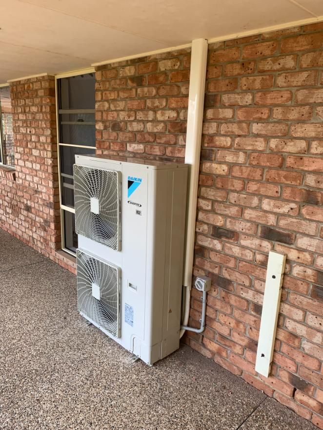 A Large Air Conditioner is Sitting on the Side of a Brick Building — Condie Refrigeration & Air Conditioning In Byron Bay, NSW
