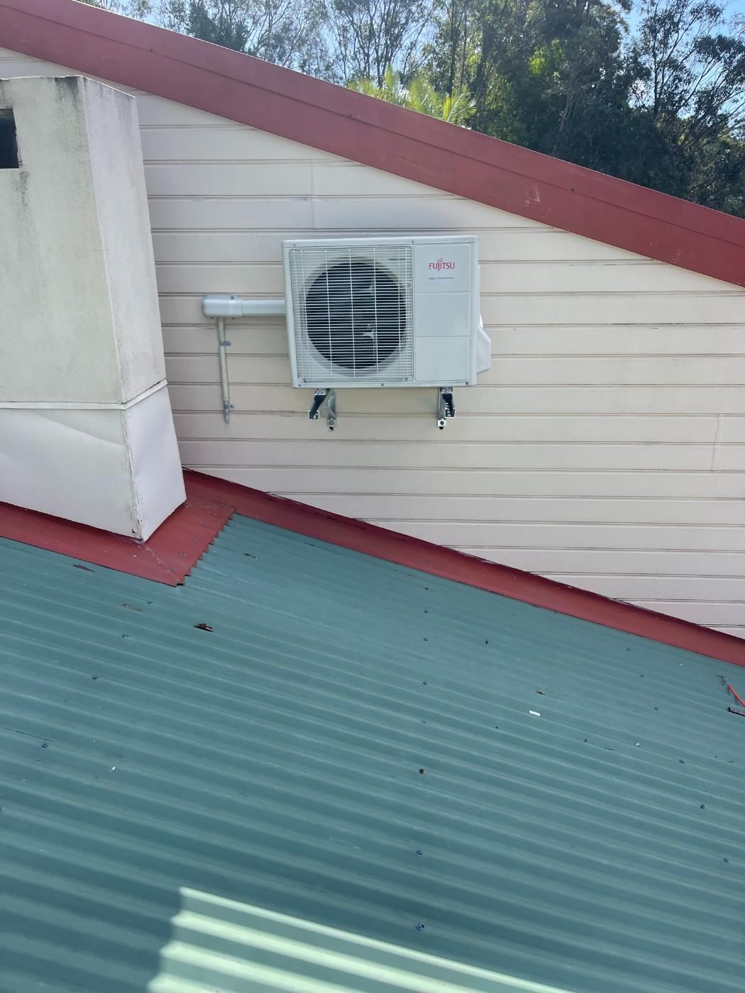 A White Air Conditioner is Mounted on the Side of a Building — Condie Refrigeration & Air Conditioning In Byron Bay, NSW