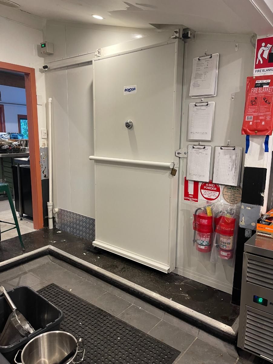 A Kitchen With a Sliding Door and Fire Extinguishers on the Wall — Condie Refrigeration & Air Conditioning In Murwillumbah, NSW