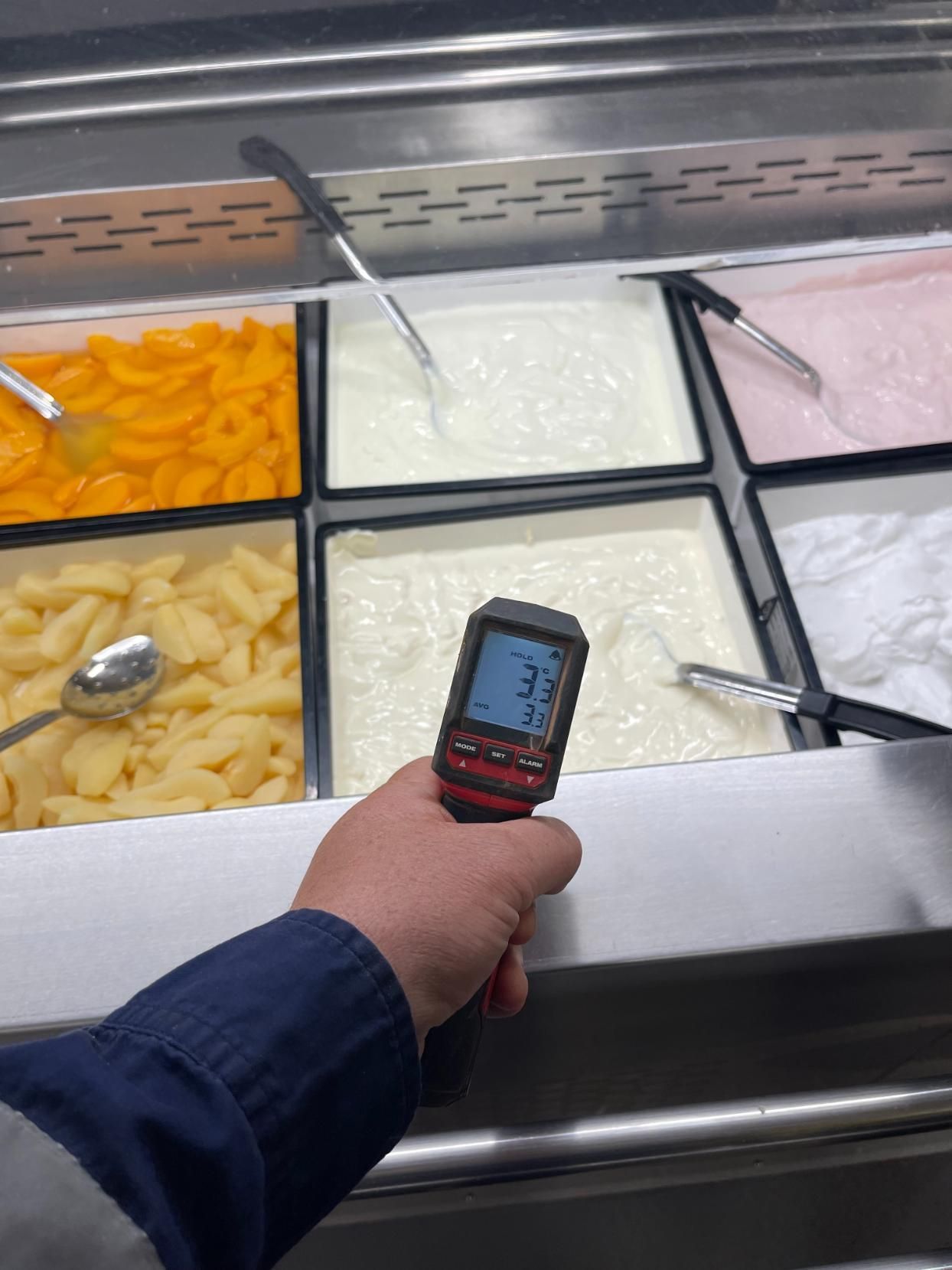 A Person is Holding a Thermometer in Front of a Buffet Line — Condie Refrigeration & Air Conditioning In Ballina, NSW