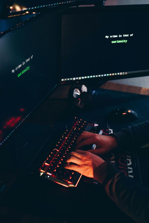 A person is typing on a keyboard in front of a computer monitor.