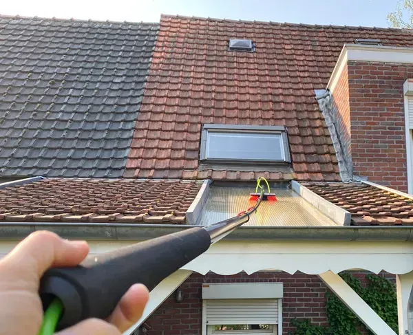 a man is kneeling on the roof of a house .