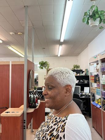 Woman with short white hair smiling in a retail store aisle under bright fluorescent lights