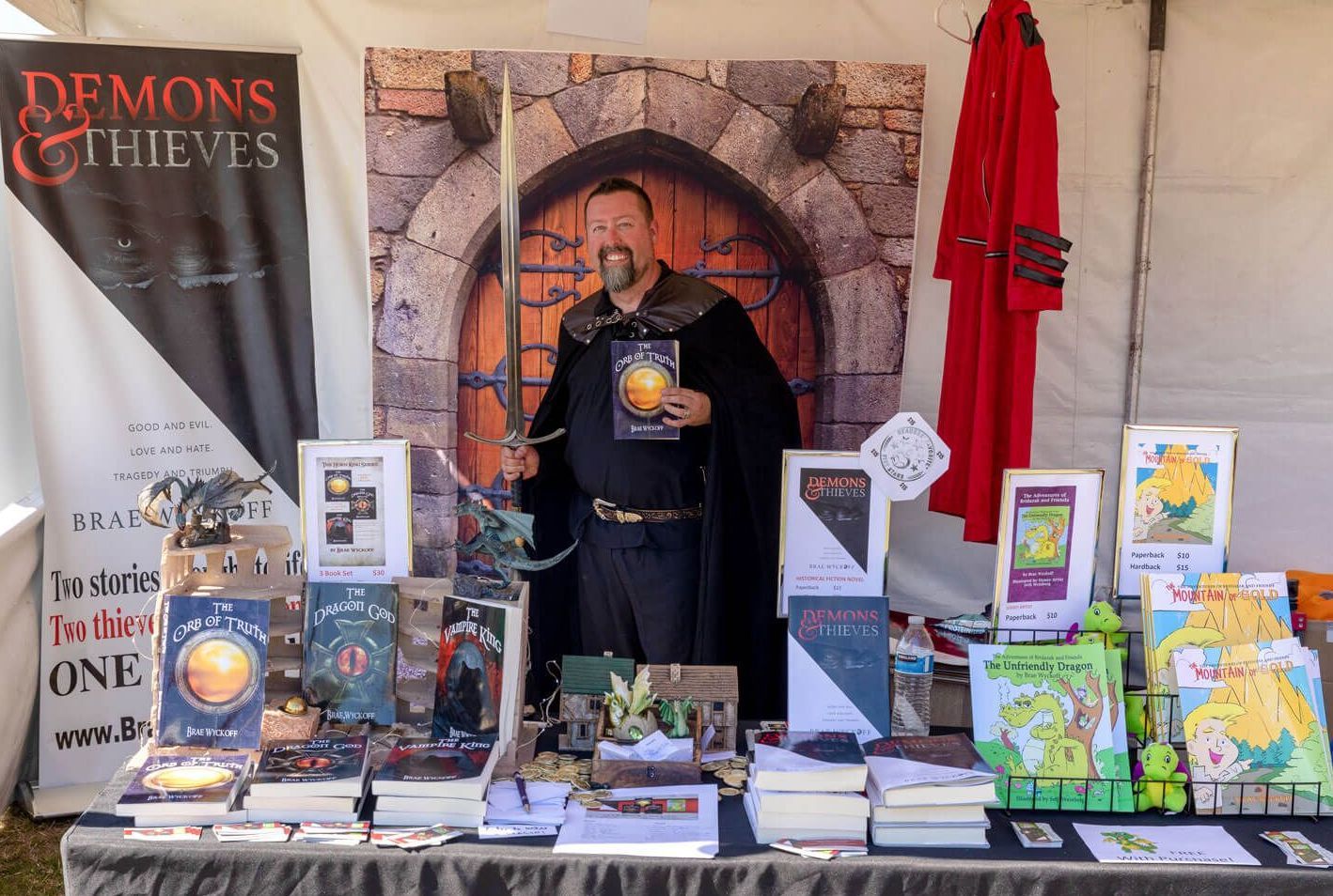 Author in costume holding a sword and promoting books. Text: Author booths