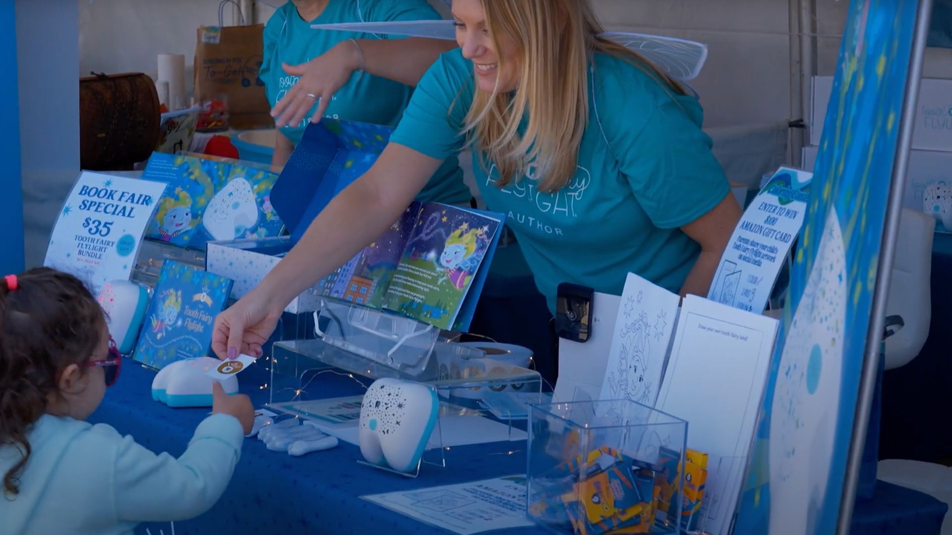 Exhibitor Toothfairy Flylight interacts with a young attendee.