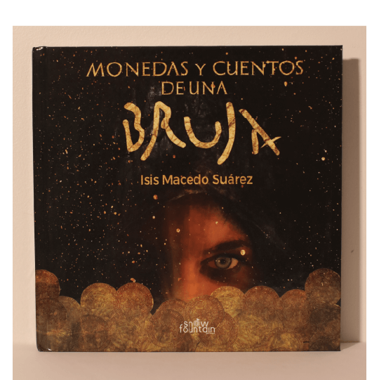 Mysterious face in the dark with one eye visible and peeking above gold coins. Text: Monedas y cuentos de una bruja.