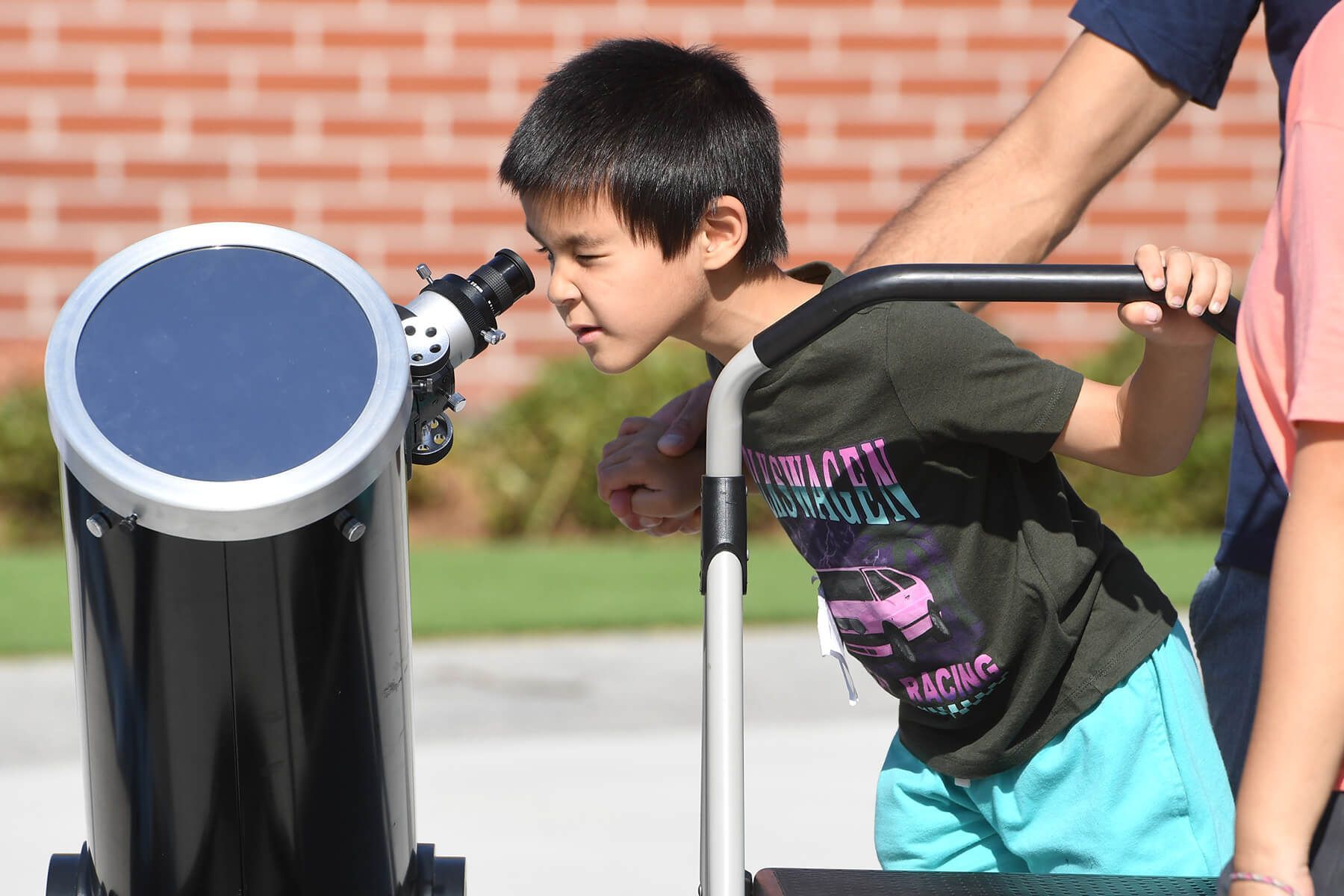 Young festival attendee looks through a large telescope.
