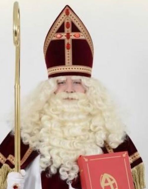 Sint Nicolaas in rode gewaden en mijter, met een staf en een rood boek in zijn handen.