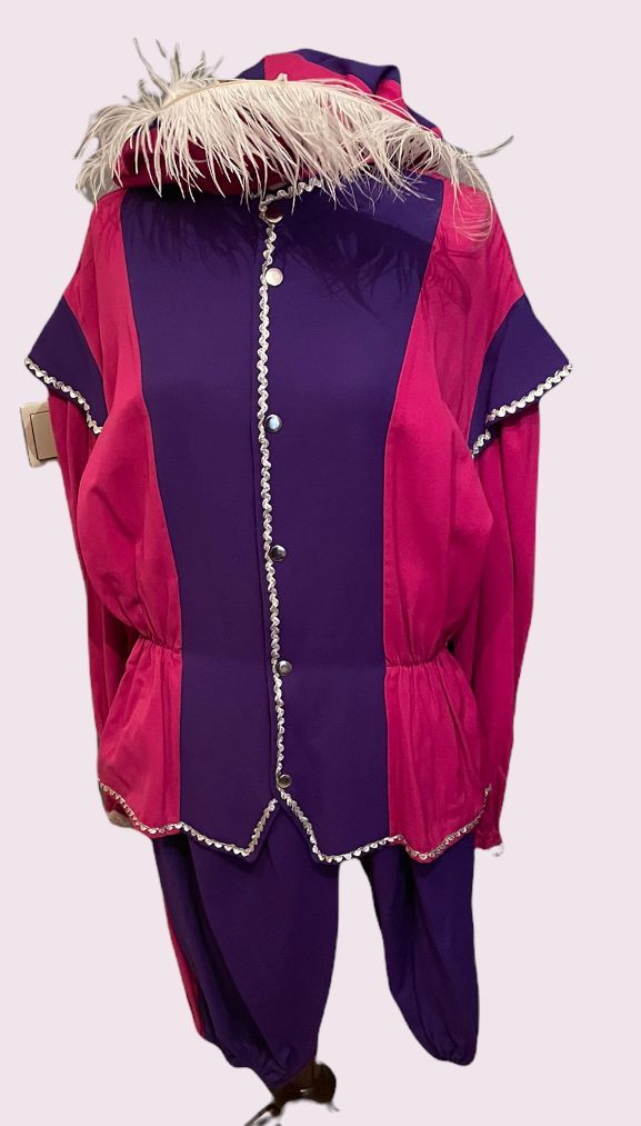 Magenta en paarse jas en broek met bontkraag op een paspop tegen een lichte achtergrond.
