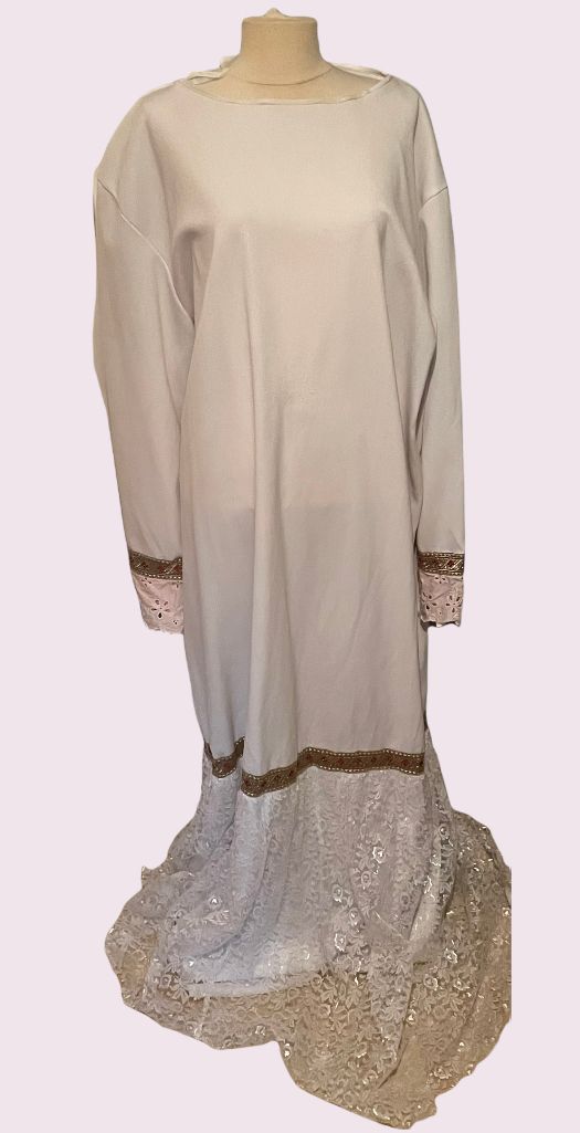 Beige jurk met lange mouwen, doorschijnende kanten manchetten en zoom, getoond op een paspop.