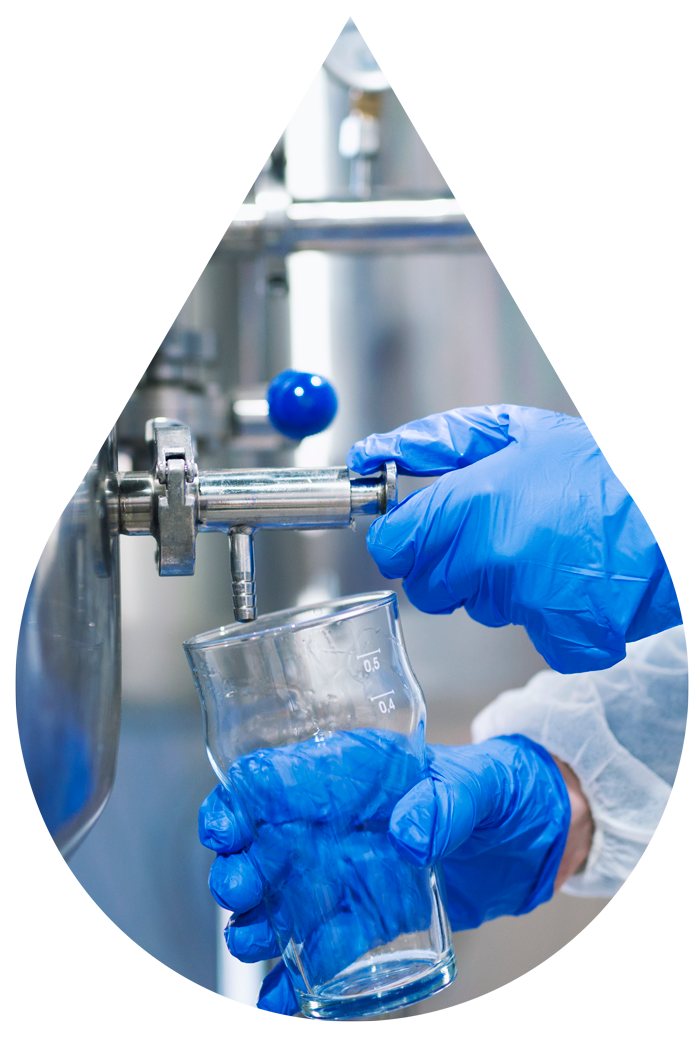 Hands in blue gloves filling glass with liquid from a dispenser at Riverwalk Water in Rosslyn, Pretoria.