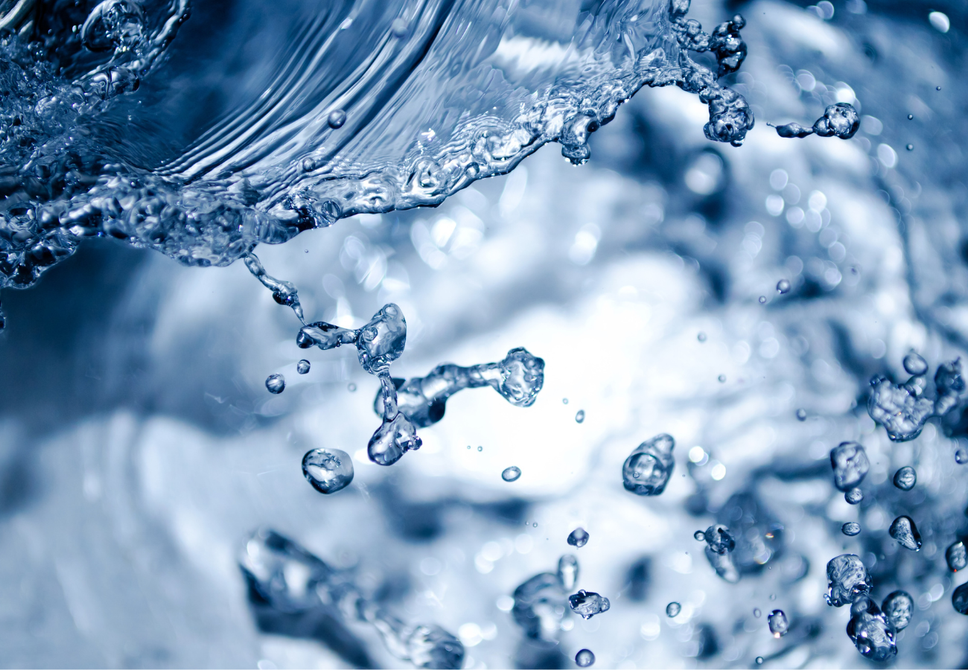 Close-up of clear water splashing with droplets and a wave.
