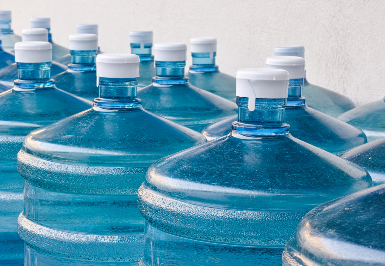 Blue water dispenser jugs with white caps, arranged closely together.