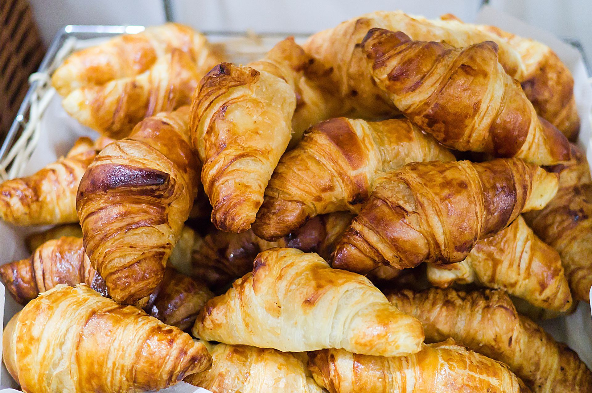 Un grande cesto colmo di una pila di croissant appena sfornati, dorati e a forma di mezzaluna.