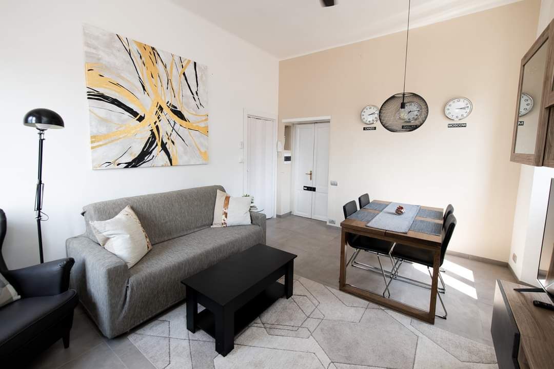 Living room with sofa, coffee table, dining table, art, and clocks on the wall.