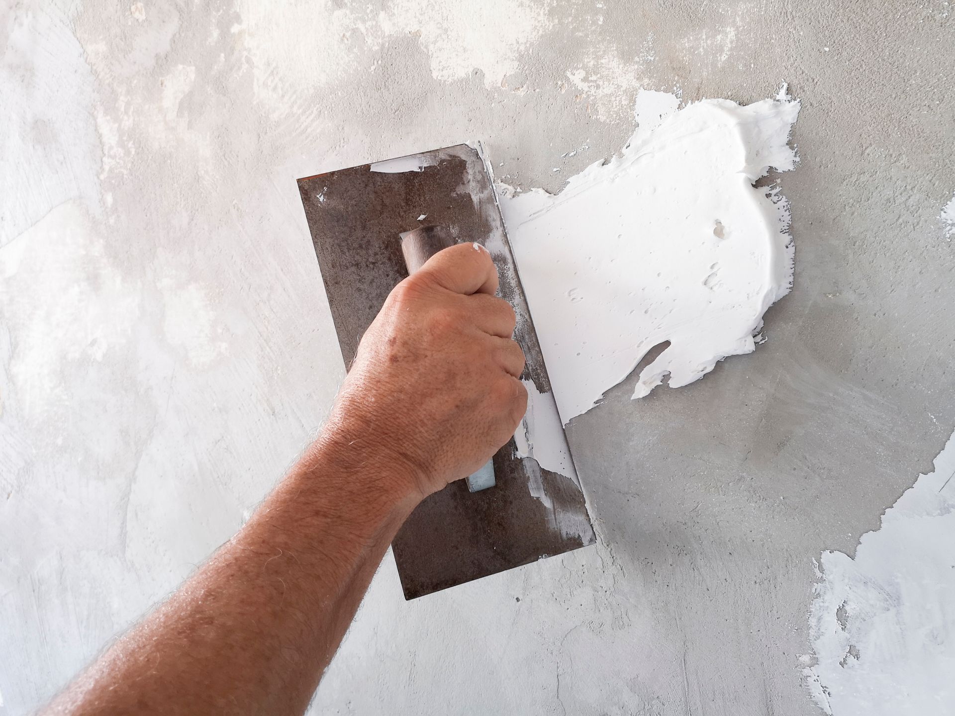 A person is plastering a wall with a trowel.