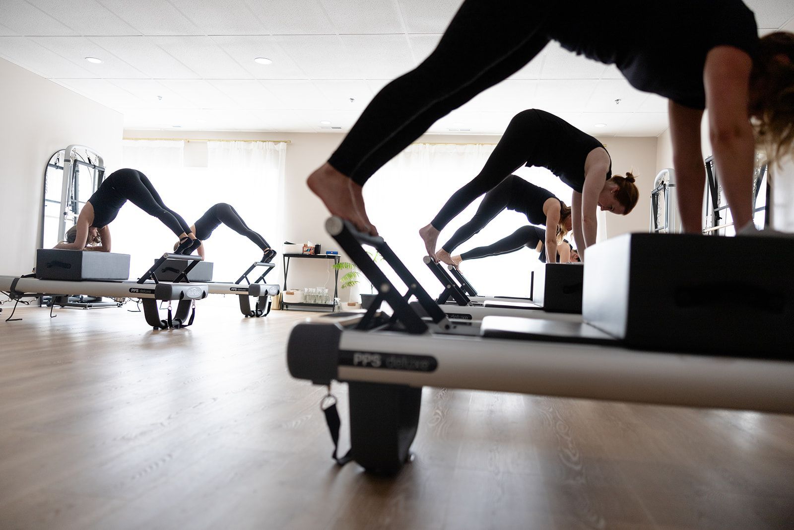 A group of people are doing exercises on pilates machines in a gym.