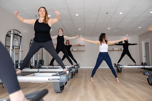 A group of women are doing exercises on pilates machines in a gym.