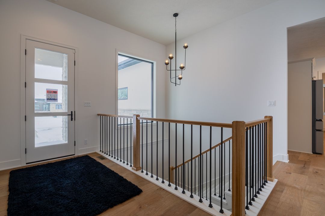 Interior view of a modern hallway with a staircase, hardwood floors, and a front door.