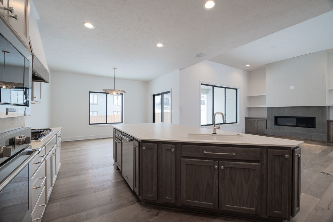 Modern kitchen with island, cabinets, and appliances. Gray island and cabinets, white countertops and walls.